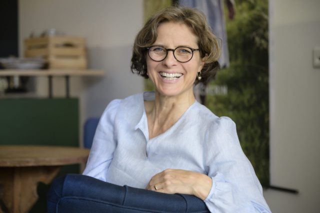 Portrait von Caroline Lauenstein sitzend und lachend in die Kamera