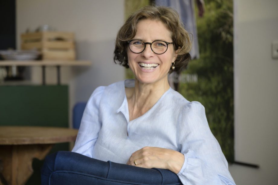 Portrait von Caroline Lauenstein sitzend und lachend in die Kamera