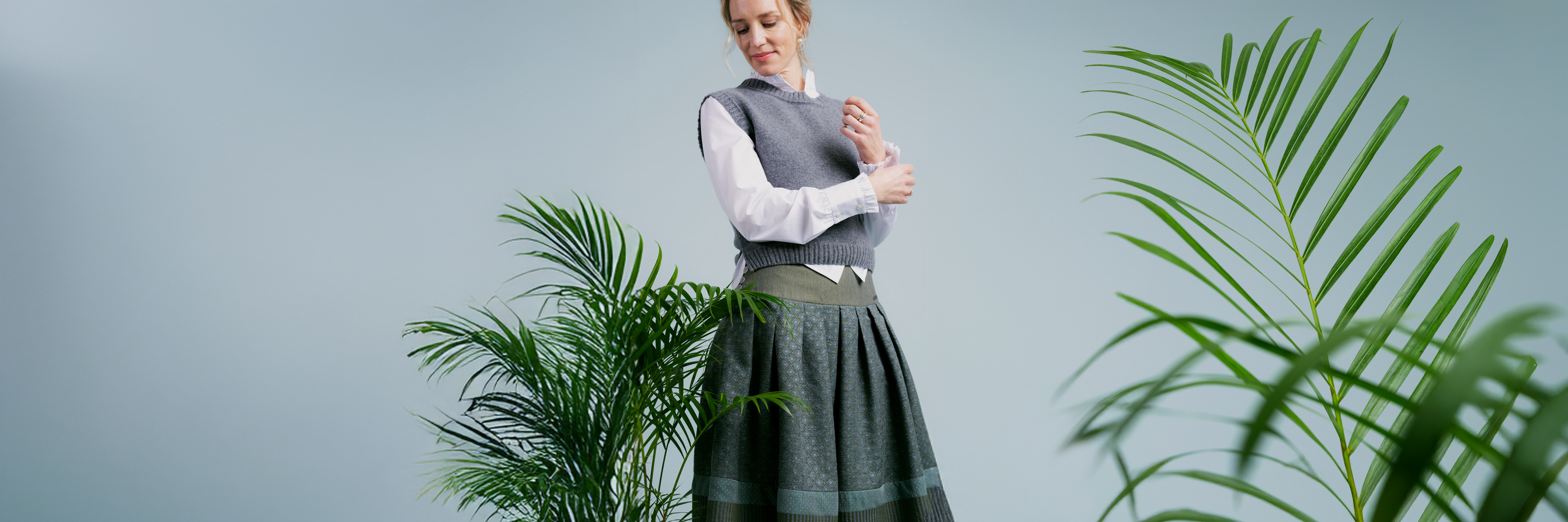 Frau trägt graugrünen Rock von Rockmacherin mit Strickpullunder, Mode zwischen Tracht und urbanem Stil.