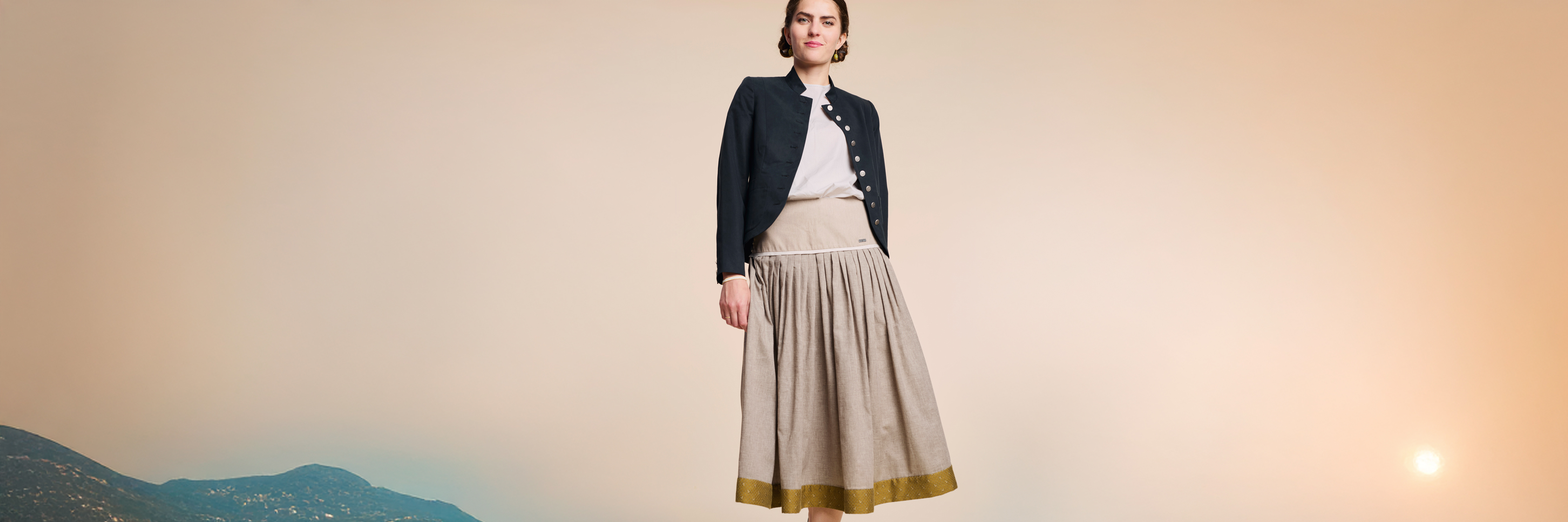 Model in einer Bergkulisse im Sonnenuntergang, mit Rock und Spenzer